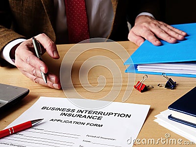 Agent offers business interruption insurance application papers Stock Photo