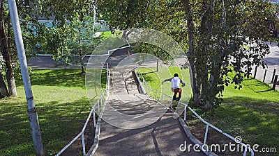 Aggressive inline roller blader grind on rail in skatepark outside. Clip. Summer extreme sport exercising outdoor in Stock Photo