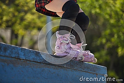 Skater girl grinding on a ledge in a outdoor skatepark in summer. Aggressive inline roller blader female performing a bs royale Stock Photo