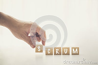 Agile and Scrum in Software Development concepts, Hand pick wooden cube and place with text to fill the word SCRUM. Brochure Stock Photo