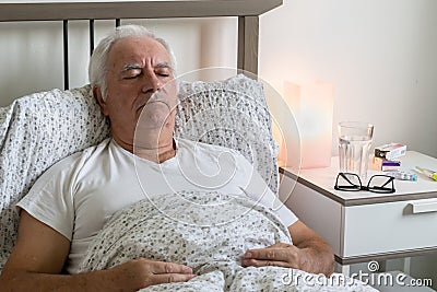 Aging senior man male bed sick ill alone retired resting unhappy sad sleeping Stock Photo