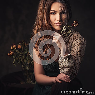 Aging, skin care concept. Half old half young woman with faded rose bouquet. Stock Photo