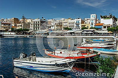 Agios Nikolaos,Crete - October 6,2019.View of small lagoon Lake Voulismeni and port with boats surrounded by several bars and Editorial Stock Photo