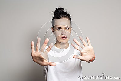 An agitated young woman put his palms forward as protection, calming someone down and looking anxiously at the camera. Isolated on Stock Photo