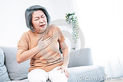 An agonizing elderly woman is experiencing chest pain. Stock Photo