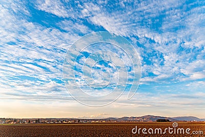 Agricultural black and brown fields and sunset in clouds Stock Photo
