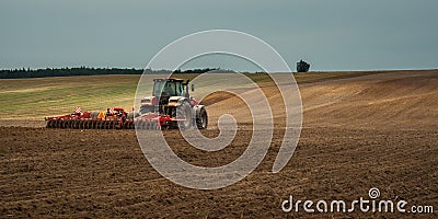 agricultural industrial landscape. a modern tractor with a trailed cultivator works on a hilly field before the autumn sowing Stock Photo