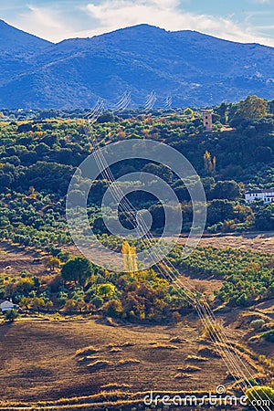 agricultural landscape with mountainous background with light cables going up to the mountain Stock Photo