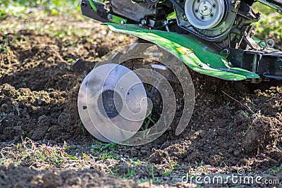 Small green plowing machine in hands of a farmer, tillage equipment, agricultural machine, agriculture, making arable in soil Stock Photo