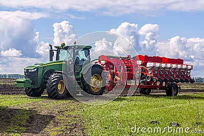 Agricultural machinery, Tractor and farmer in agricultural fields of wheat and rapeseed Editorial Stock Photo