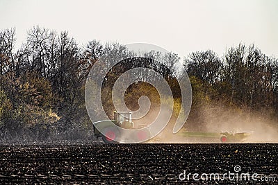 Agricultural tractor with seeder is working in the field Stock Photo