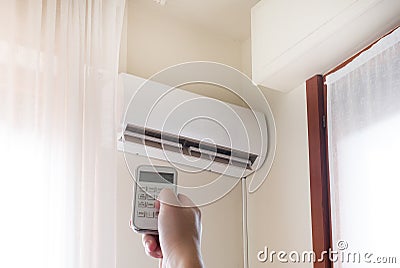 Air conditioner and hand with temperature remote control Stock Photo