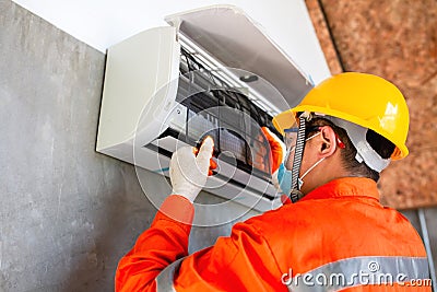 Air conditioner technician mechanic wearing mask and helmet to prevent disease, Covid 19 Currently to install dust filter for air Stock Photo