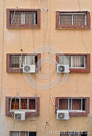 Air conditioning external units with large fans on old building facade wall near windows, many untidy cables near Stock Photo