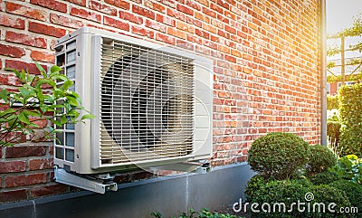 Air conditioning heat pump outdoor unit against brick wall. Stock Photo