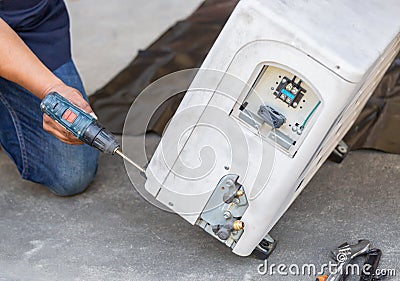 Air Conditioning Repair, technician man hands using a screwdriver fixing modern air conditioning system Stock Photo