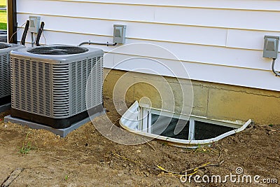 Air conditioning system assembled on performing preventive maintenance on window well for basement construction new residential Stock Photo