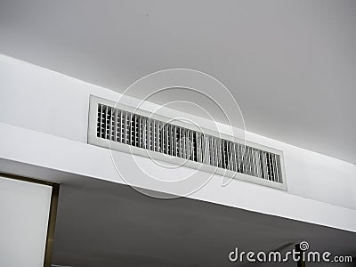 Air conditioning wall mounted ventilation system on ceiling in the white hotel room. Stock Photo