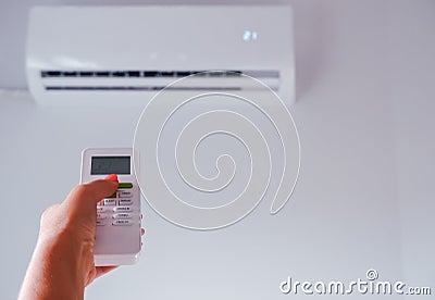 Air conditioning. A woman holds a remote control from an air conditioner in her hands. Wall mounted air conditioner unit in the Stock Photo