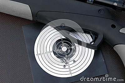 Air gun, paper shooting target with bullet holes and airgun pellets Stock Photo