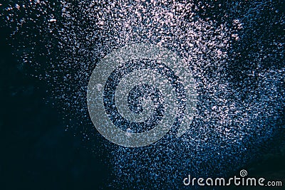 Air oxygen bubbles floating swimming up and boiling dark blue deep water forming different shapes some in focus blur coming up on Stock Photo
