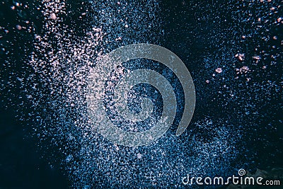 Air oxygen bubbles floating swimming up and boiling dark blue deep water forming different shapes some in focus blur coming up on Stock Photo