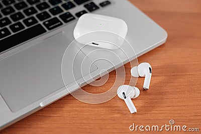 Air Pods Pro. macbook. with Wireless Charging Case. New Airpods pro on wooden background. Airpods. Copy space Editorial Stock Photo