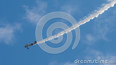 A small biplane airplane doing acrobatic stunts against the blue sky Editorial Stock Photo