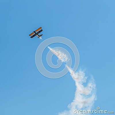 A small biplane airplane doing acrobatic stunts against the blue sky Editorial Stock Photo