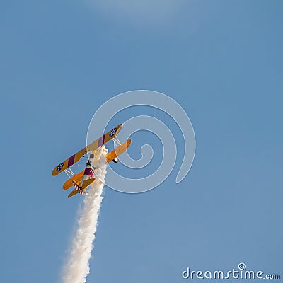 A small biplane airplane doing acrobatic stunts against the blue sky Editorial Stock Photo