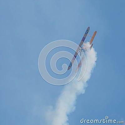 A small biplane airplane doing acrobatic stunts against the blue sky Editorial Stock Photo