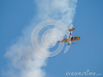 A small biplane airplane doing acrobatic stunts against the blue sky Editorial Stock Photo