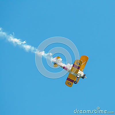 A small biplane airplane doing acrobatic stunts against the blue sky Editorial Stock Photo