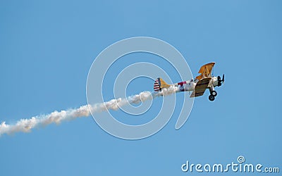 A small biplane airplane doing acrobatic stunts against the blue sky Editorial Stock Photo