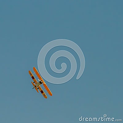 A small biplane airplane doing acrobatic stunts against the blue sky Editorial Stock Photo