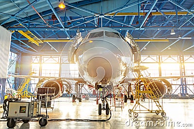 Aircraft in the aviation industrial hangar on maintenance, outside the gate bright light Stock Photo