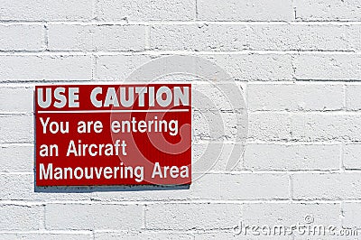 Aircraft manouvering red and white warning sign hung on painted brick wall. Stock Photo