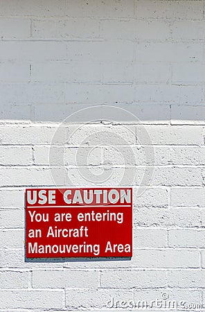 Aircraft manouvering red and white warning sign hung on painted brick wall. Stock Photo
