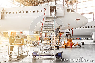 Aircraft is under repair, technical inspection is a working technician. A view of the nose, a cockpit of pilots with a staircase l Stock Photo