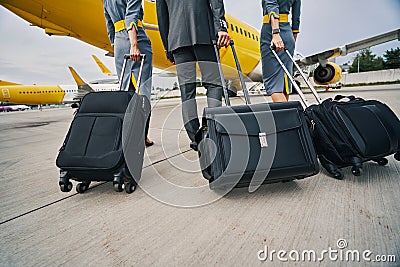 Aircrew with their baggage walking towards the landed airplane Stock Photo