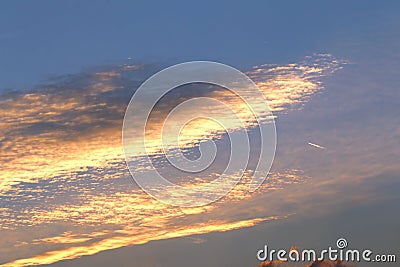Airliner and clouds illuminated by the setting sun Stock Photo