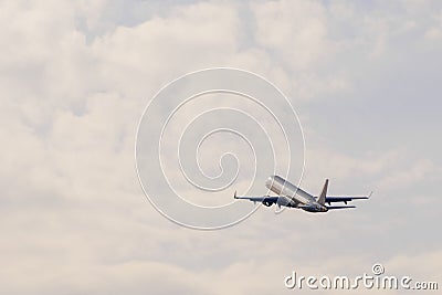 An airplan goes towards the clouds at sunset after take off Stock Photo