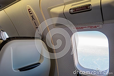 Airplane cabin passenger seat next to emergency exit with signs and instructive writings Editorial Stock Photo