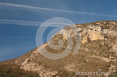 Airplane, contrails of another airplanes and cliff. Stock Photo