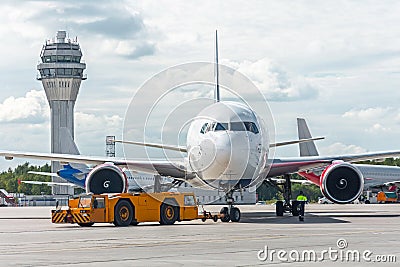 Airplane execute push back operation at airport, on the background ATC tower. Editorial Stock Photo