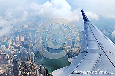 Airplane flies over Hong Kong. Passenger jet plane flying above urban scene. Stock Photo