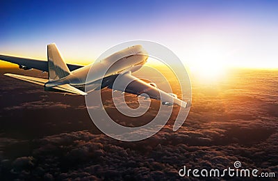 Airplane flying above clouds during sunset Stock Photo