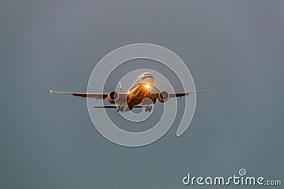 Airplane in the grey sky at night with headlight Stock Photo