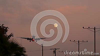 Airplane landing in LAX airport at sunset, Los Angeles, California USA. Passenger flight or cargo plane silhouette, dramatic Stock Photo