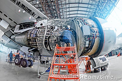 Airplane mechanic diagnose repairs jet engine through open hatch. Stock Photo